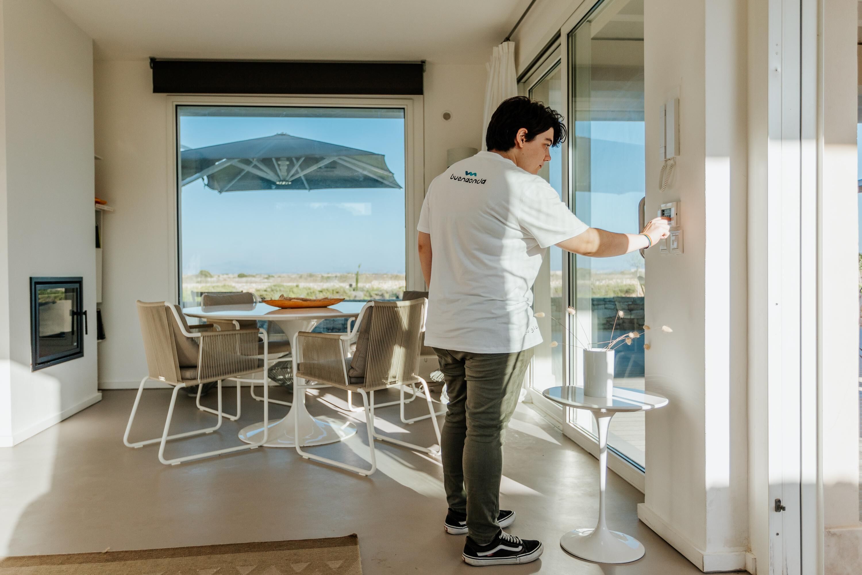 Un interior moderno con un amplio ventanal corredera, un comedor con mesa y sillas, y vistas al paisaje desértico.