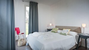 A hotel room with a bed, two bedside lamps, a nightstand, a chair, and a window with curtains.