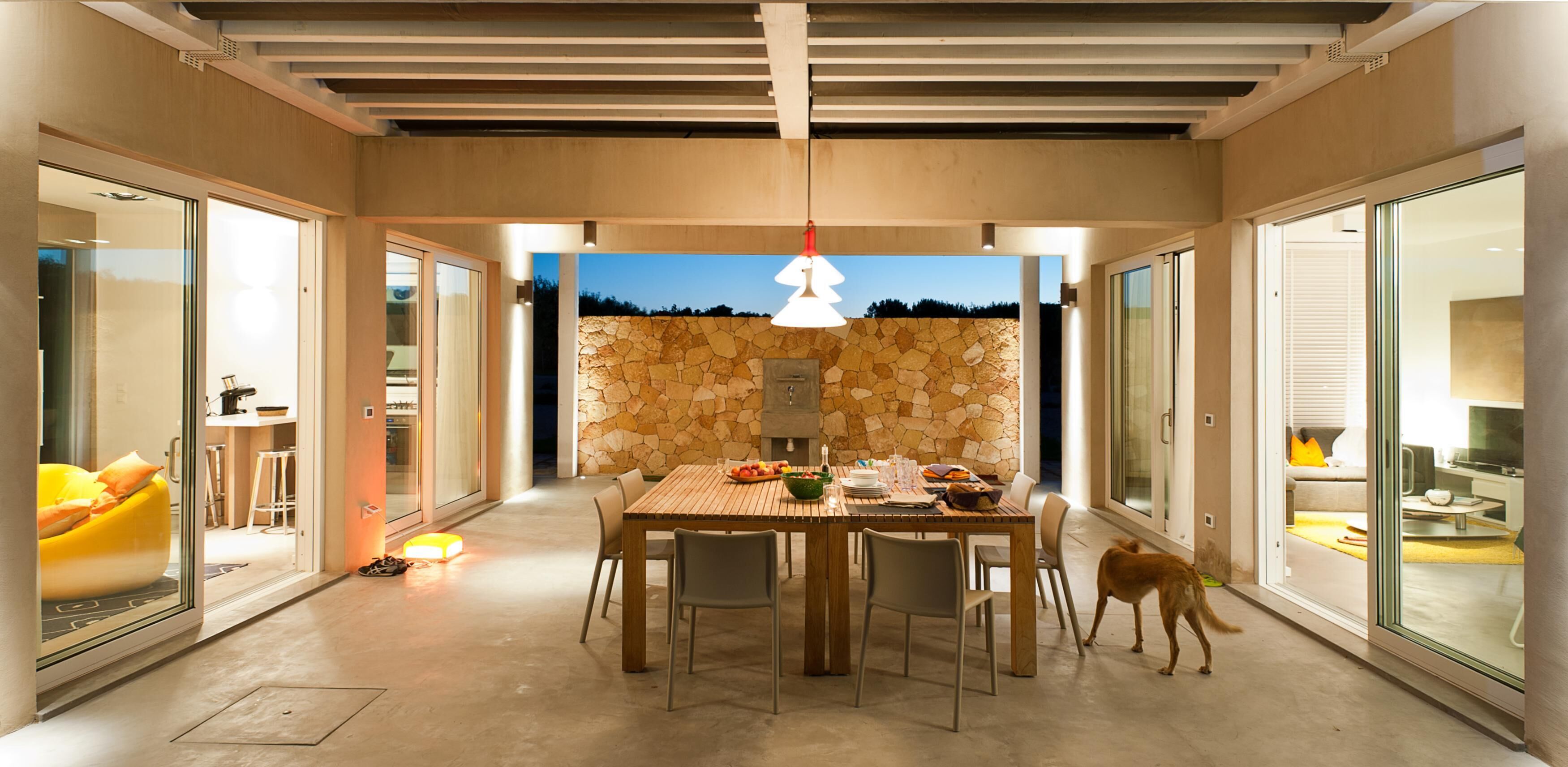 A modern dining area with a stone wall, a wooden table, and chairs.