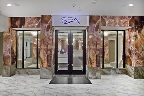 A spa entrance with a marble facade, a reception desk, and a modern interior design.
