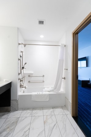 A modern bathroom with a bathtub, shower, and toilet.