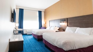 Habitación de hotel con dos camas, un escritorio, una silla, un televisor y una ventana con cortinas.