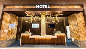 Una recepción de hotel con una lámpara moderna, un letrero que indica servicios de SPA y una pantalla digital.