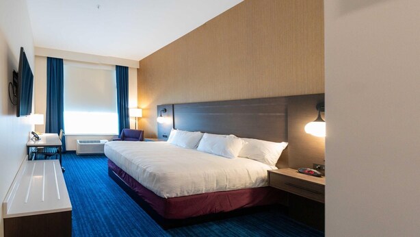 Una habitación de hotel con una cama grande, mesitas de noche, un escritorio y un televisor de pantalla plana.