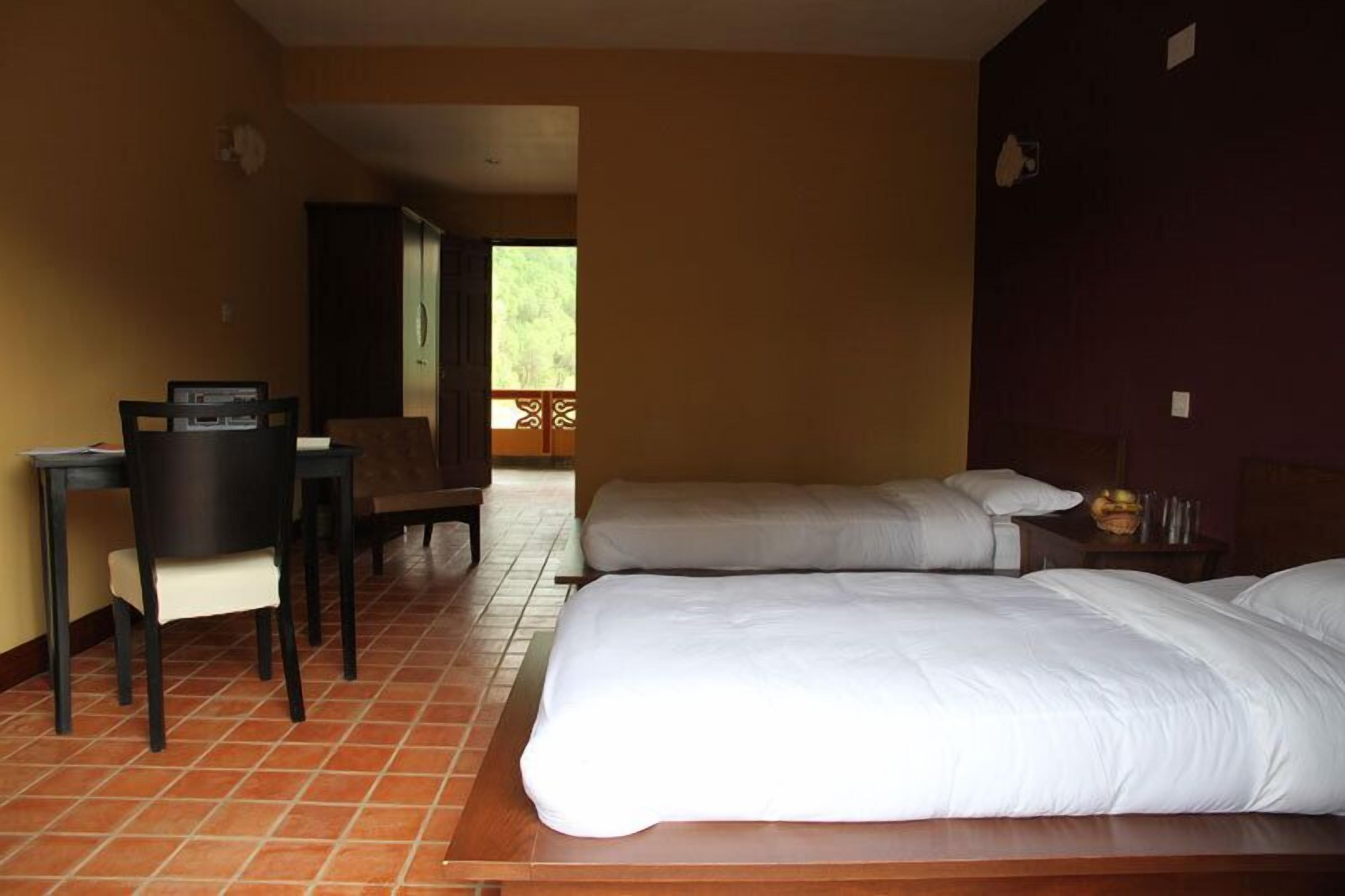 A hotel room with two beds, a desk, and a chair.