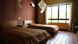 A room with two beds, a window with curtains, and a mosquito net. - Neydo Hotel Buddhist Monastery (Dakshinkali)