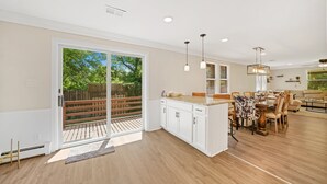 Una cocina amplia con una isla grande, puertas corredizas de vidrio a una terraza y un comedor con candelabro.