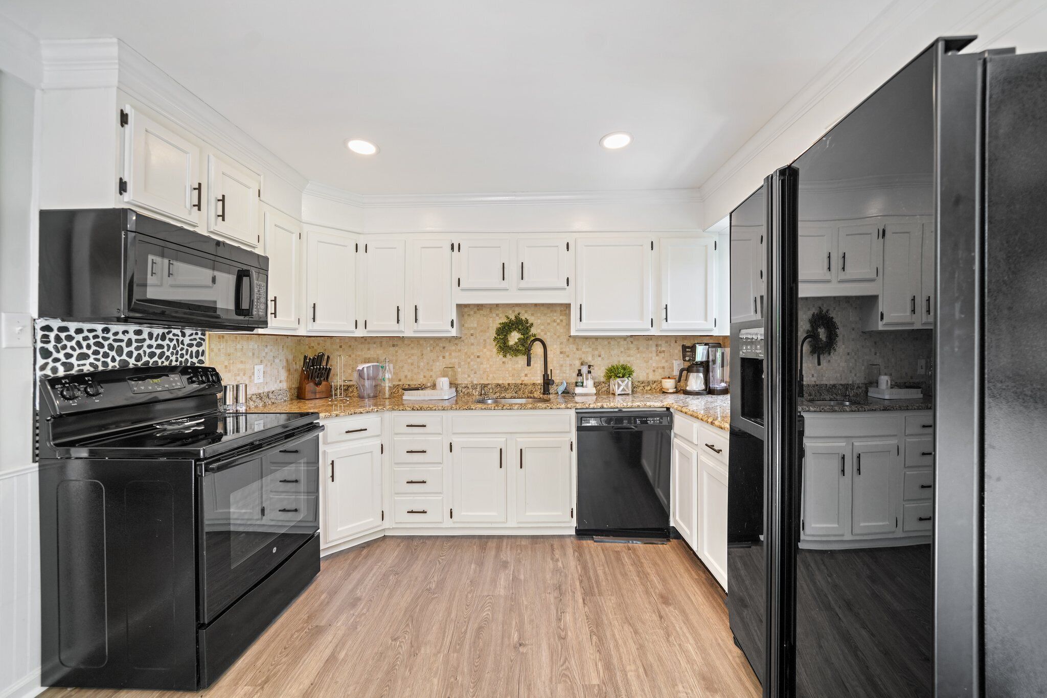 A modern kitchen with white cabinets, a black stove, and a black dishwasher.