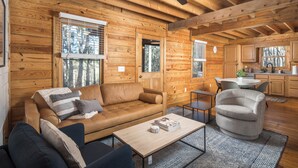 A cozy log cabin interior with a wooden dining area, a sofa, and a coffee table.