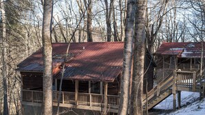 A cabin with a wooden deck and a staircase leading to a second level.