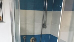 Una doccia con piastrelle blu e bianche, una porta in vetro e un soffione metallico.