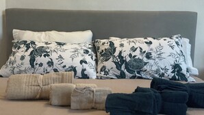 Un letto rifatto con cuscini a fiori, una coperta beige e asciugamani arrotolati.