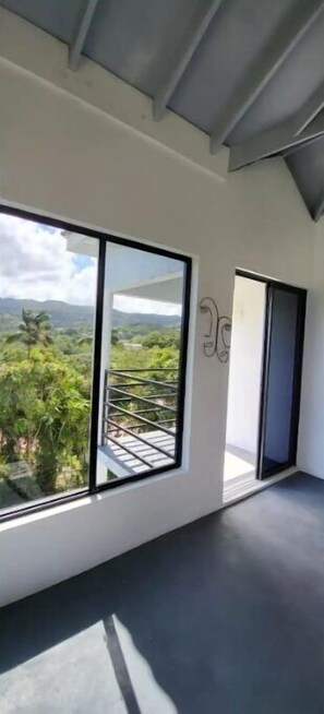 Un intérieur moderne avec de grandes fenêtres donnant sur un paysage verdoyant et des montagnes.