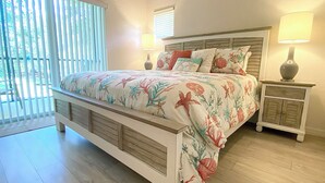 A bedroom with a bed, nightstands, and a window with blinds.