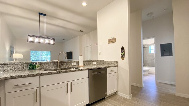 A modern kitchen with granite countertops, white cabinetry, and a built-in dishwasher.