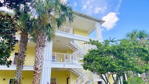 A multi-story hotel with a yellow facade, white balconies, and a central staircase.