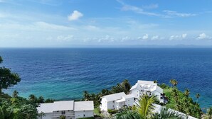 A coastal view with white buildings, palm trees, and a clear blue sea. - Wake Up At Paradise (Santa Barbara Samana)