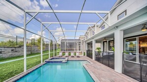 En swimmingpool med et overdækket område, liggestole og en terrasse med et hegn.