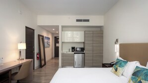 A hotel room with a bed, desk, chair, kitchenette, and a view of the hallway. - Relaxing Resort Like Stay On The Beach-CS41 (Hollywood)