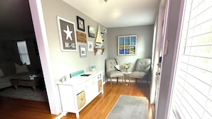 Un salon avec une console blanche, deux fauteuils, une petite table sur laquelle est posé un vase, et un tapis.