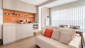 Una cocina moderna con armarios blancos, un salpicadero de ladrillo y una zona de comedor con una mesa dispuesta para dos.
