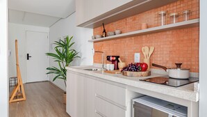 Una cocina moderna con armarios blancos, un salpicadero de ladrillo y un horno empotrado.