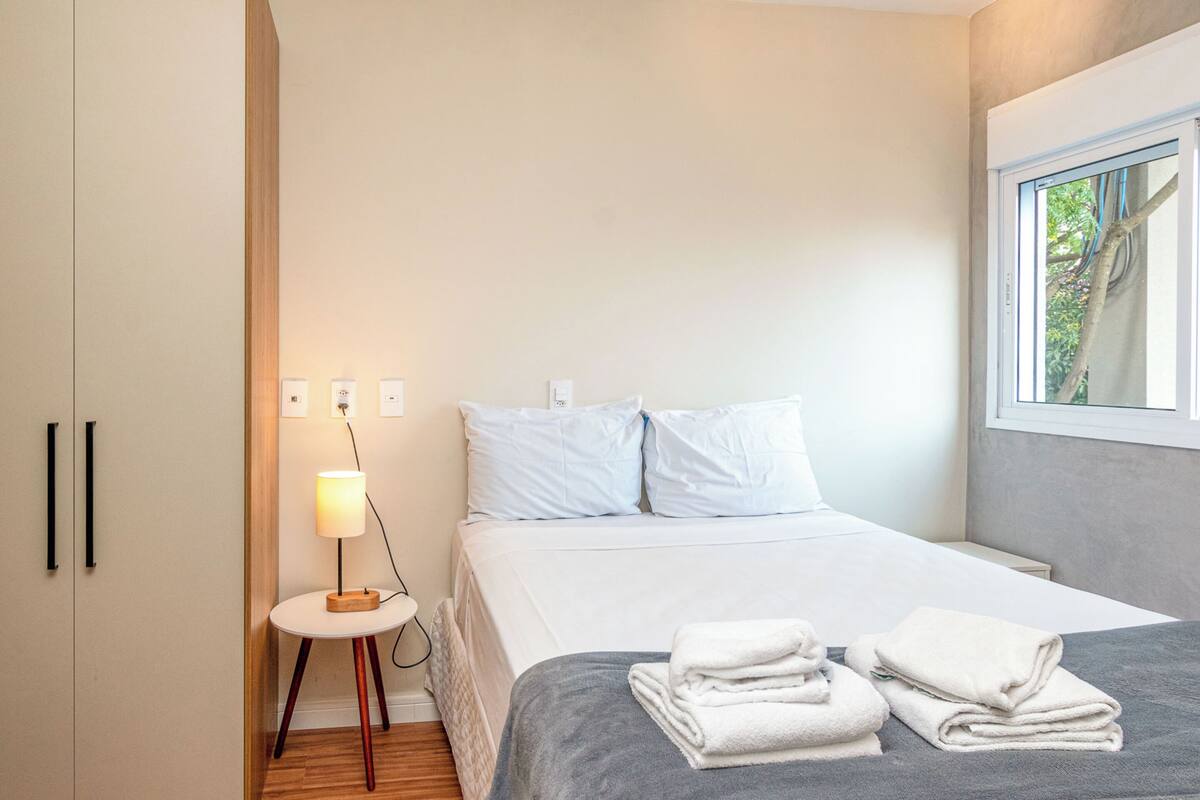 Ein modernes Schlafzimmer mit Bett, Nachttisch, Lampe und Handtüchern.