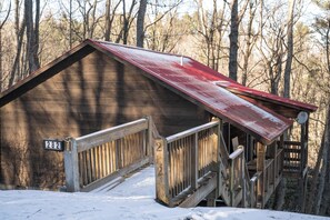 A wooden cabin with a red roof, a wooden staircase, and a number sign '282' on the railing. - Red Feather Cabins 282 (Boone)