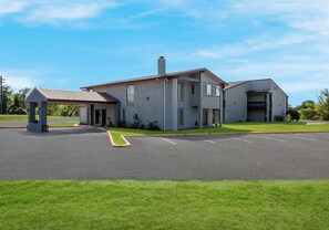 A two-story building with a covered entrance and a parking lot in front. - Red Roof Inn Madisonville (Madisonville)