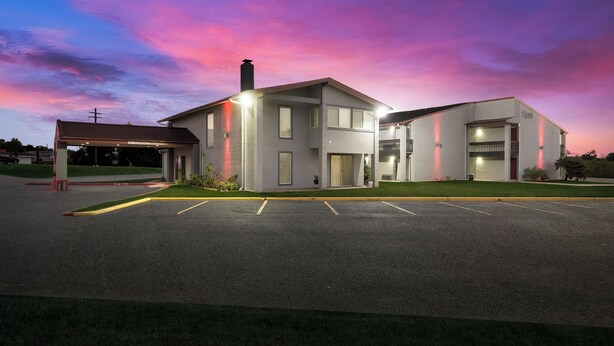 A two-story building with a covered parking area and a clear sky. - Red Roof Inn Madisonville (Madisonville)