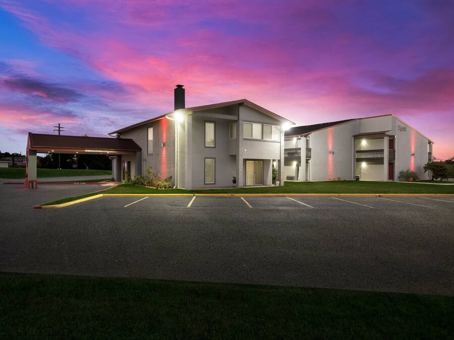 A modern building with a covered entrance, a parking lot, and a well-maintained lawn.