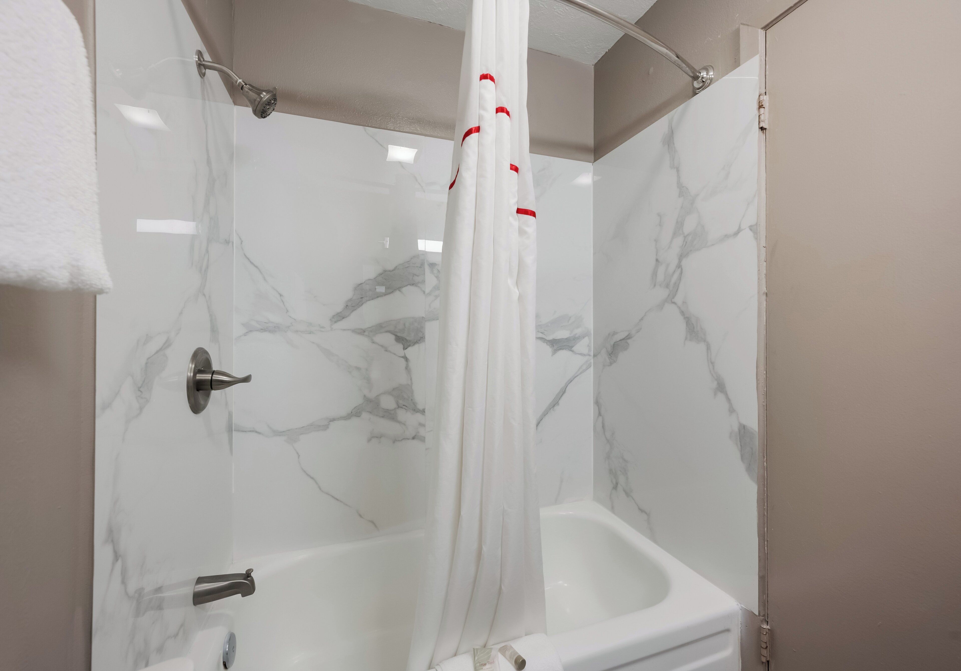 A bathroom with a shower curtain, a bathtub, and a toilet.