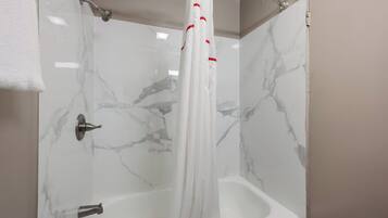 A bathroom with a shower curtain, a bathtub, and a toilet.