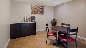 A dining area with a round table, two chairs, a dark wooden cabinet, and a wall-mounted coffee machine. - Red Roof Inn Madisonville (Madisonville)