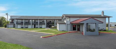 A building with a parking lot, a fire lane, and a small entrance with a red 'OPEN' sign.