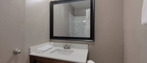 Un baño con un lavamanos blanco, un espejo y un dispensador de papel higiénico.