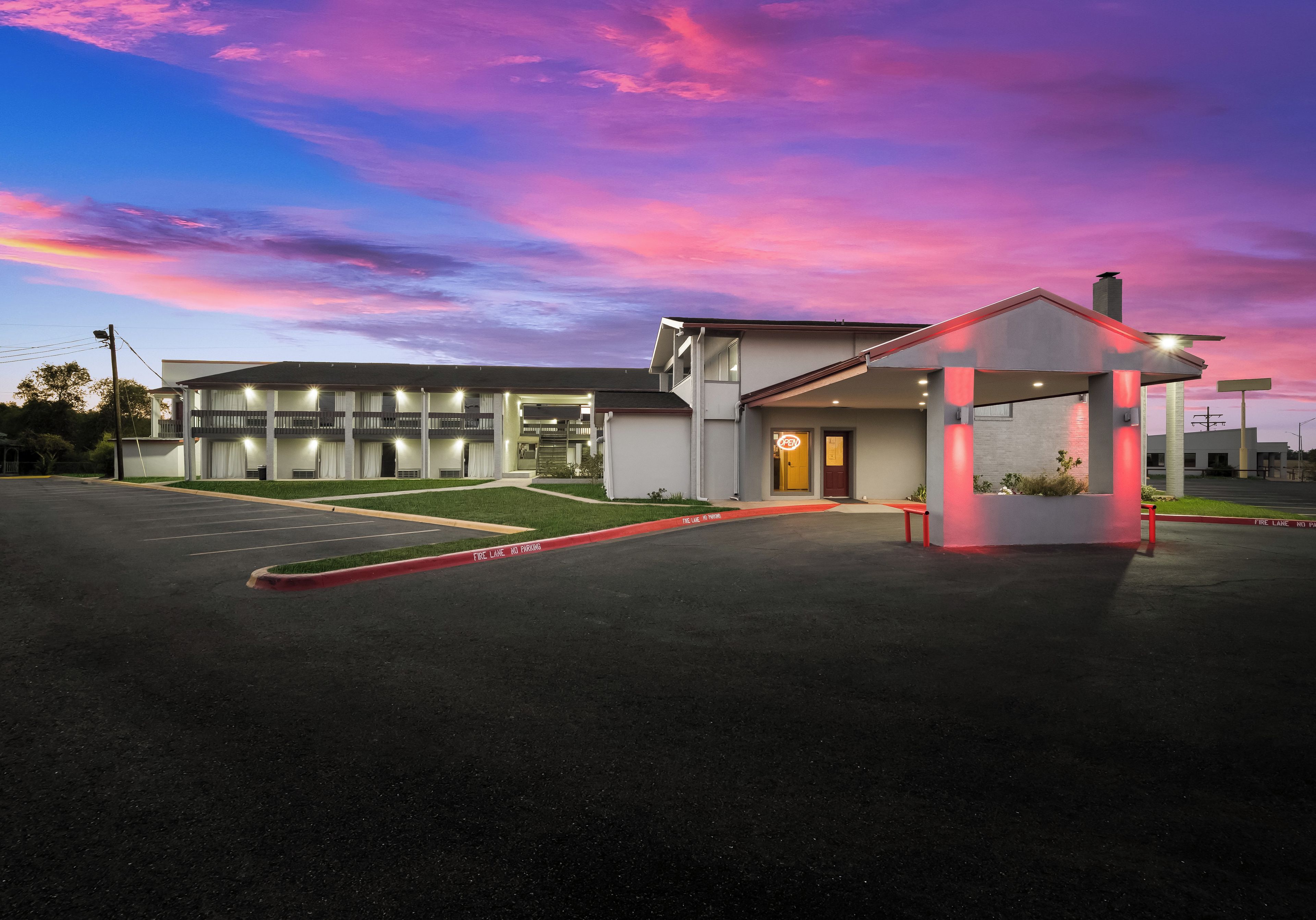 Ein Motel mit überdachtem Parkplatz, ein mehrstöckiges Gebäude und ein klarer Himmel.