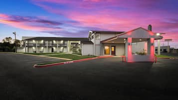 A motel with a covered parking area, a building with multiple floors, and a clear sky.