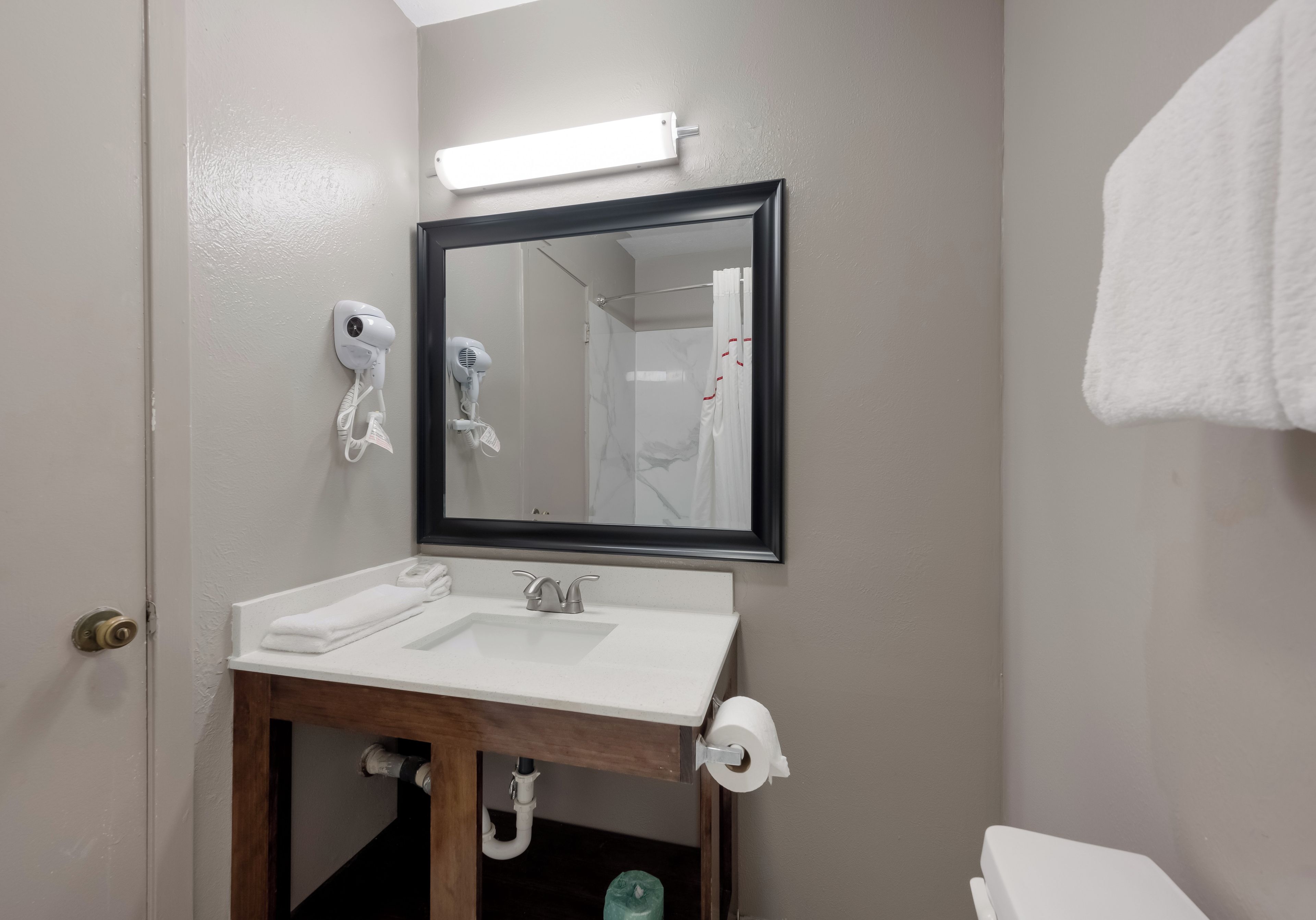 A bathroom with a white sink, a mirror, a hairdryer, and a toilet.