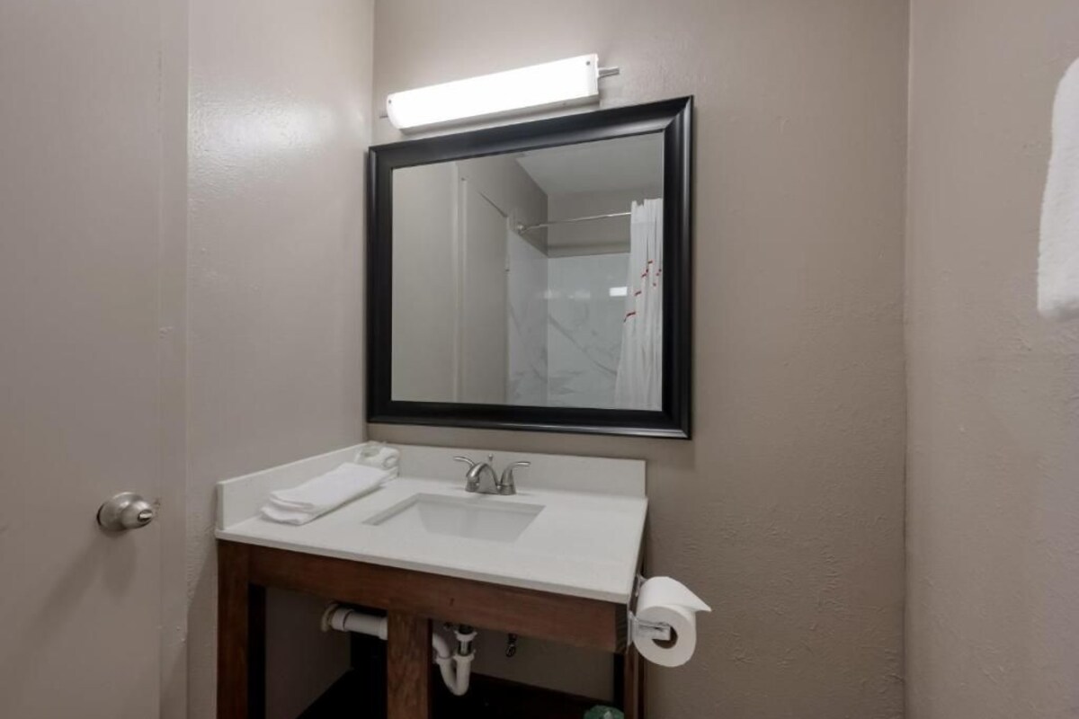 Un baño con un lavamanos blanco, un espejo y un dispensador de papel higiénico.