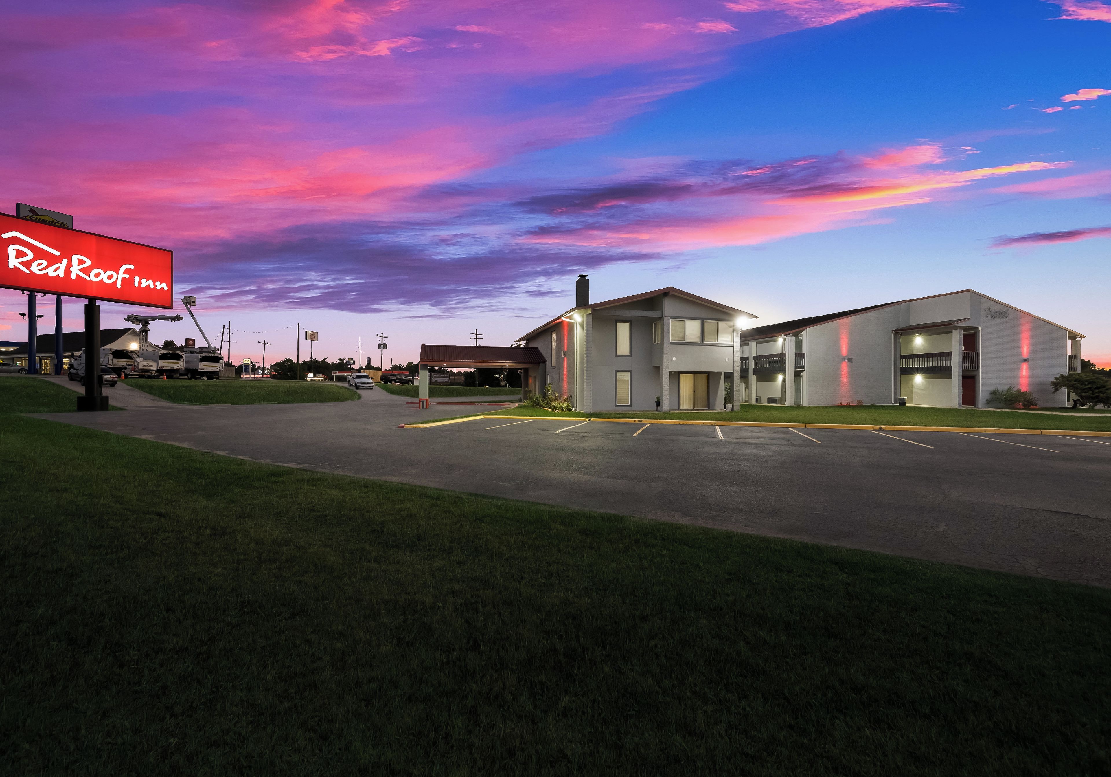 A Red Roof Inn with a parking lot and a building with a flat roof.