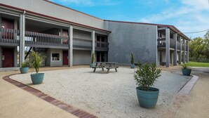 A building with multiple balconies, a gravel courtyard, and potted plants. - Red Roof Inn Madisonville (Madisonville)