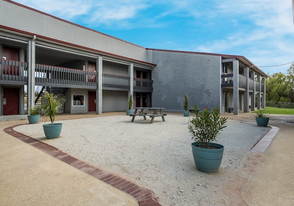 Un edificio moderno con numerosi balconi, un cortile in ghiaia e piante in vaso.