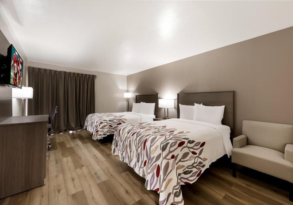 Une chambre d’hôtel avec deux lits, un bureau, un canapé et une télévision.