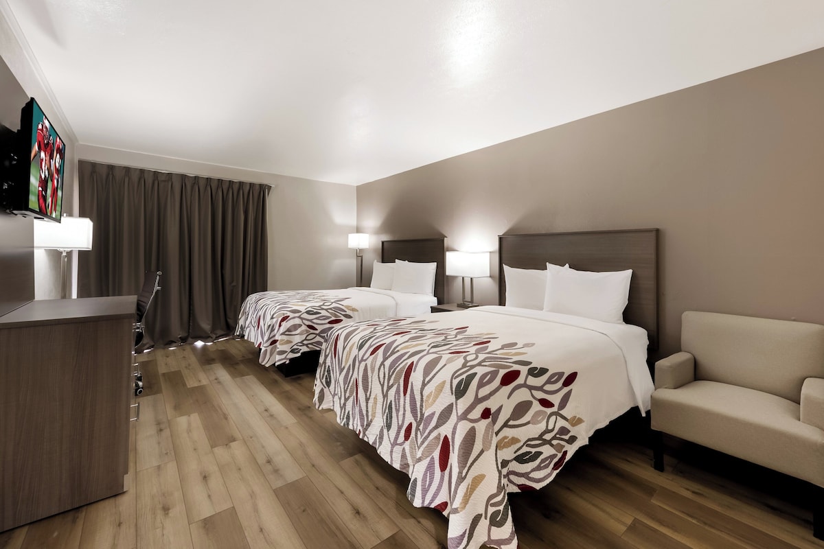 A hotel room with two beds, a desk, and a sofa.
