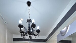 Ein modernes Badezimmer mit einem Glaswaschbecken, einem großen Spiegel, einer Chandelüster und einer Duschkabine.