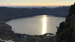Ein See, umgeben von Hügeln, mit einem kleinen Dorf im Vordergrund.