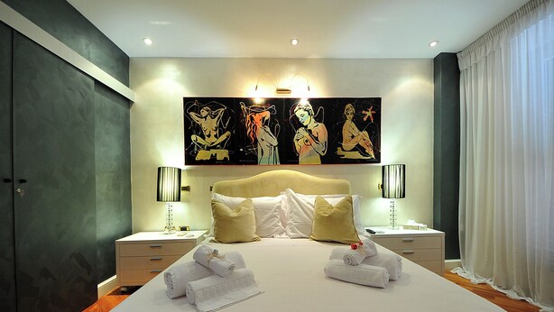 Ein Hotelzimmer mit einem großen Bett, zwei Nachttischen, einer Kopfteil und einem Gemälde an der Wand.