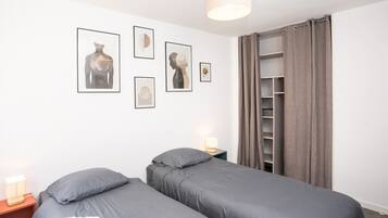 Une chambre avec deux lits, une armoire et des œuvres d’art murales.