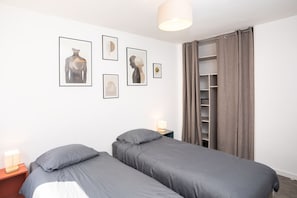 Een slaapkamer met twee bedden, een kledingkast en decoratie aan de muur.
